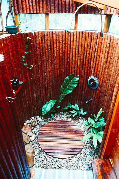 outdoor shower with natural wooden walls and rocks on the ground