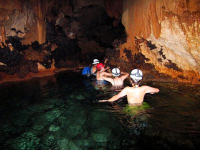 ATM Cave exploration by Pat people in waist deep water with helmets exploring cave