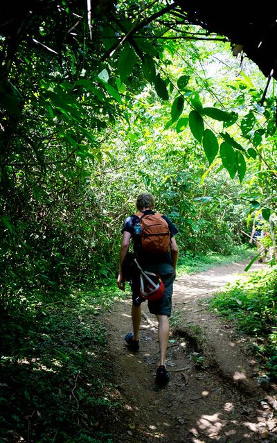 man with orange backpack hiking through forest