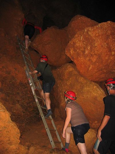 ATM Cave ladder climb by Dave Scott people with red helmets climbing ladder in a cave