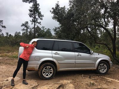 woman in front of grey parked car in the rainforest