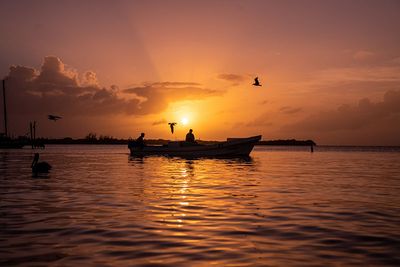 silhouette of two people riding boat during sunset