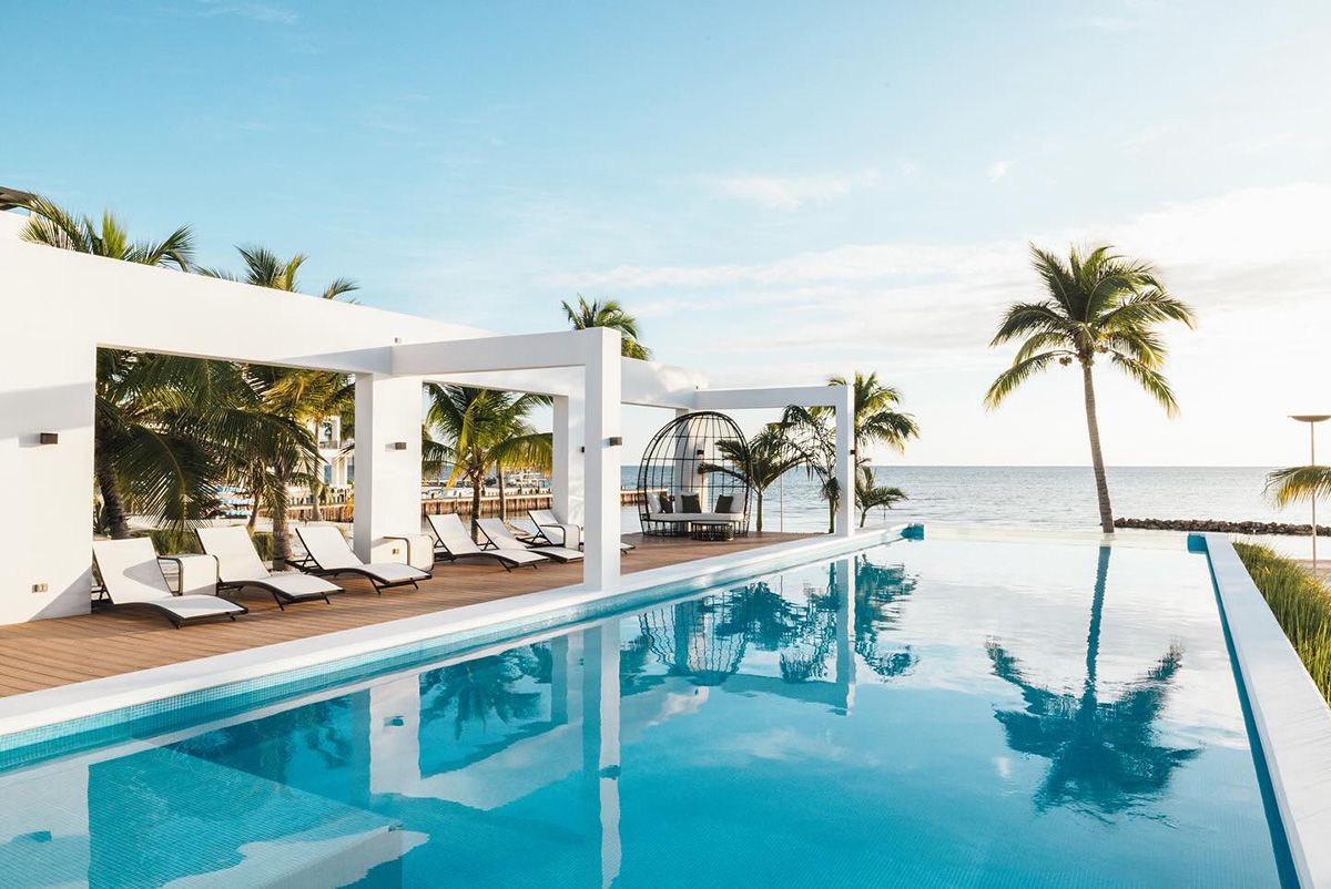 infinity pool surrounded by chairs and sea backdrop