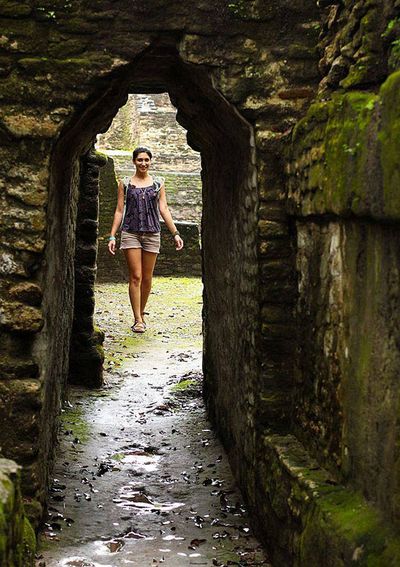 women framed with a mayan ruin arch with moss on it