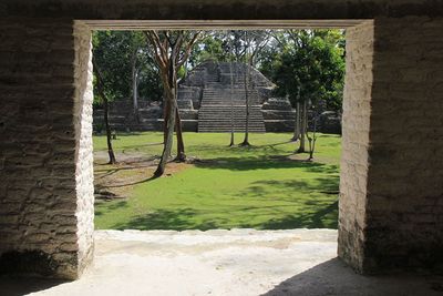 squared doorway with view to mayan ruin with trees in front