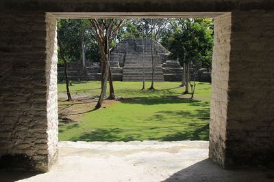 Cahal Pech from the inside of a doorway by Standa Vrzala squared doorway with view to mayan ruin with trees in front