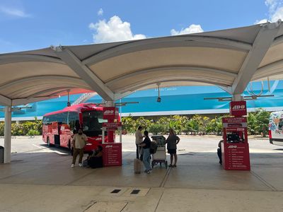 ADO Bus Terminal at Cancún Airport outdoor parking space with ticket booth and bus