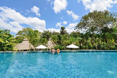 infinity pool with jungle backdrop and thatched houses in background