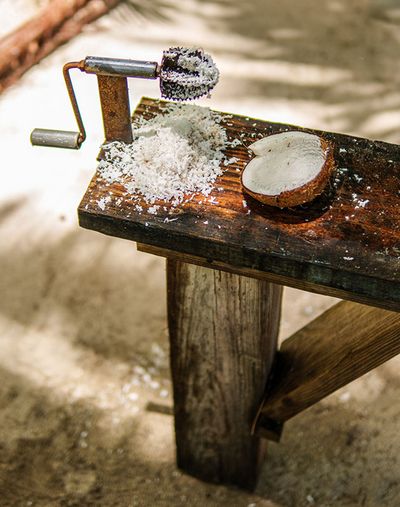 half grinded coconut on the table with a manual hand grinder
