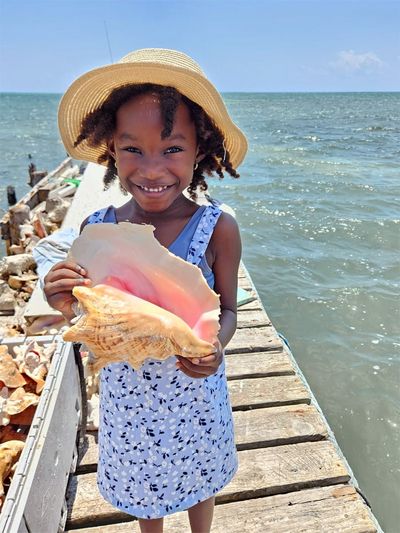 girl holding conch shell on dock