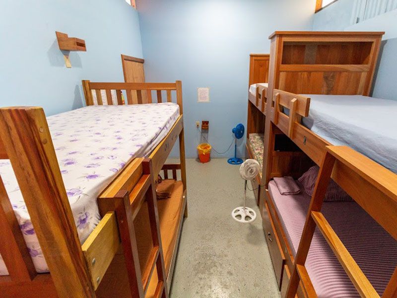 three sets of wooden bunk beds along with two tiny fans