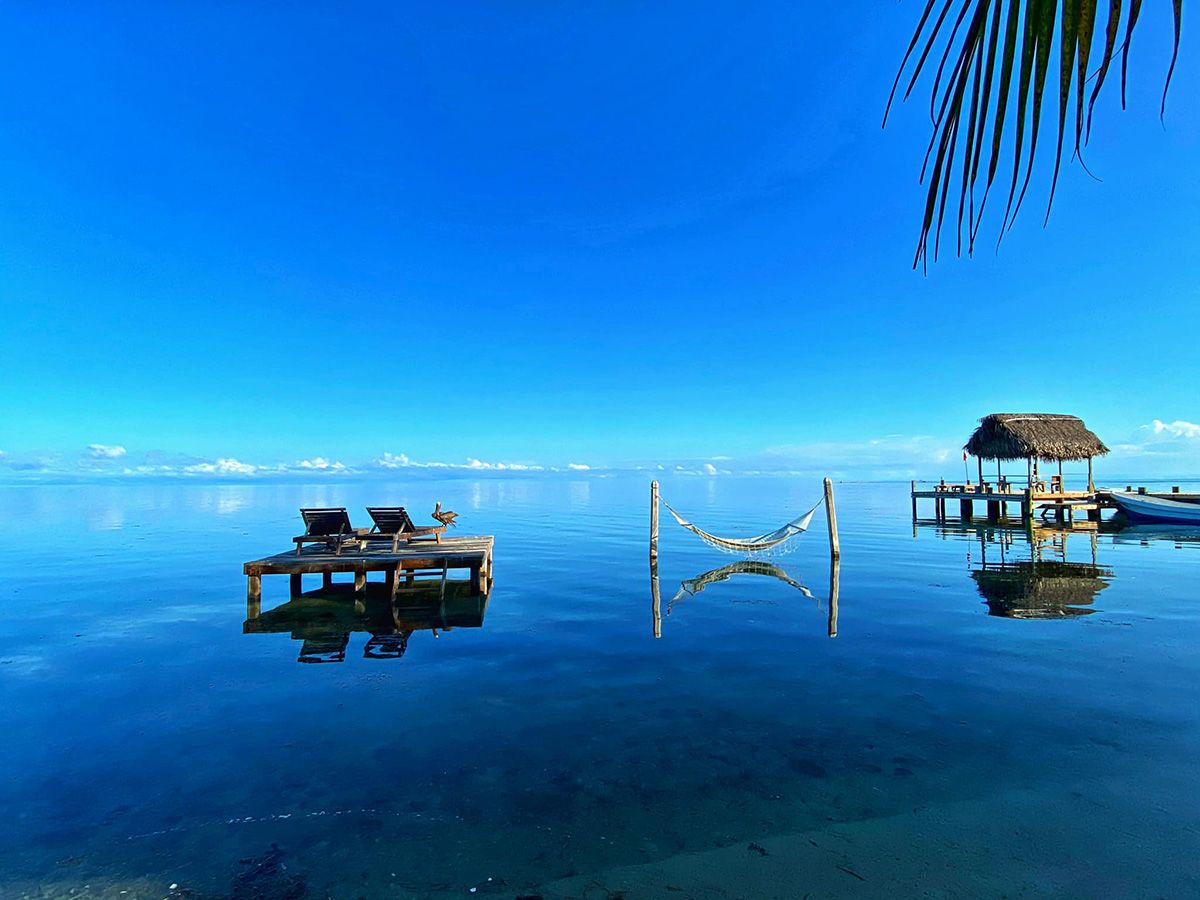 mirror like shore water with hammock and small dock in water