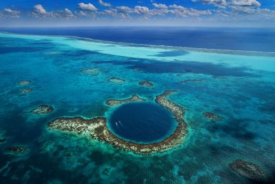 Great Blue Hole in Belize by Kasia Kaczyลska aerial shot of blue sinkhole with two boats inside it