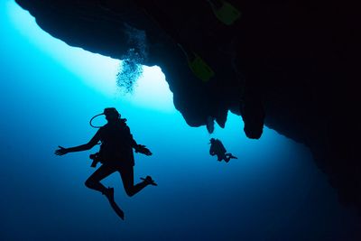 Scuba divers at Great Blue Hole by Keith Levit two scuba divers below cave structure