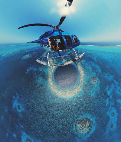 blue helicopter over large blue hole with fish eye view