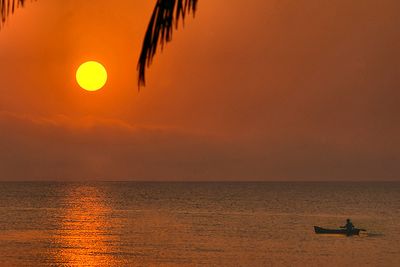 red sunrise with man canoeing in water