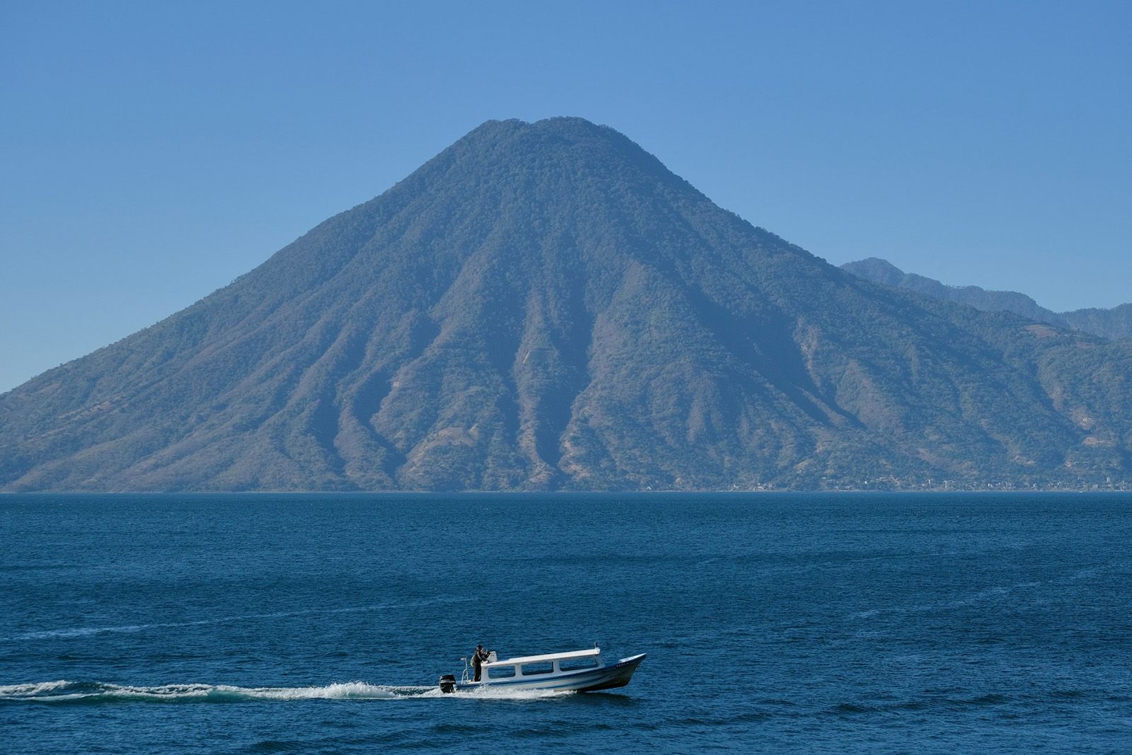 boat in front of big lake with volcanos