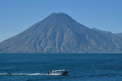 boat in front of big lake with volcanos