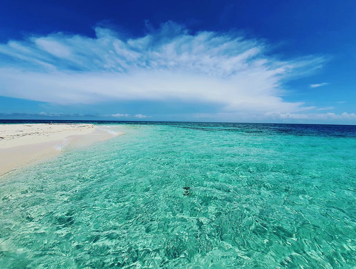 turquoise water by beach and blue sky