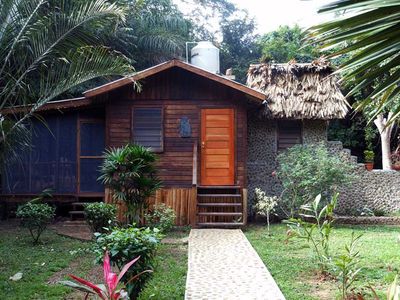 tiny cabin with red rood and thatched roof beside stoned room with thatched roof