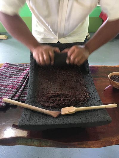 hands grinding chocolate on a rock