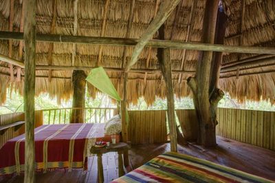 second floor open bedroom with two beds and thatched roof