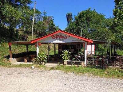 small white and red shack with trees up front