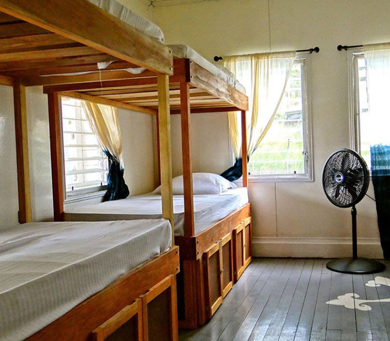 two wooden bunk beds with a black fan on the side