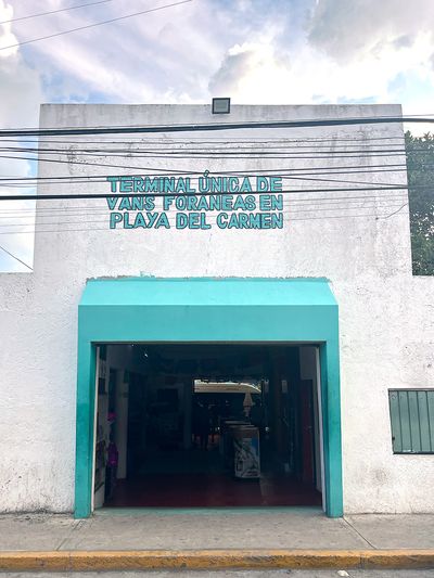 Terminal for Playa Del Carmen To Tulum Colectivo white building entrance with aquamarine arc