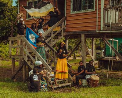Proud Garifuna people of Belize by Delly SixMilly traditionally dressed men and women with instruments and food on stairs