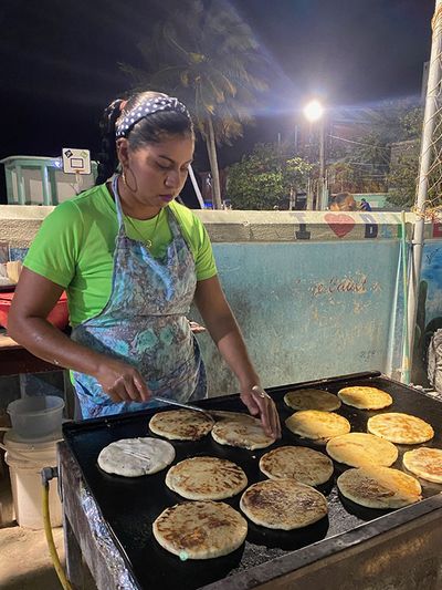 lady preparing pupusas on grill