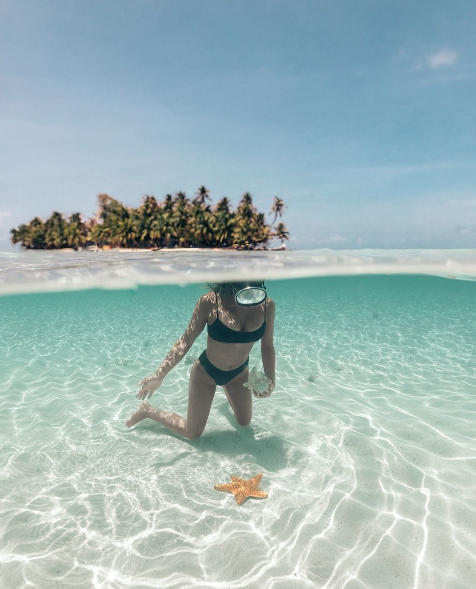 woman snorkeling touching starfish with island above