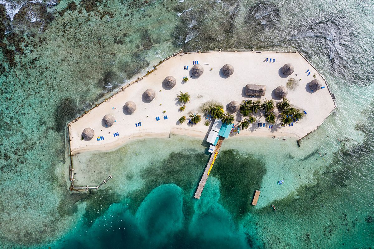white beach island with tiny thatch houses and dock