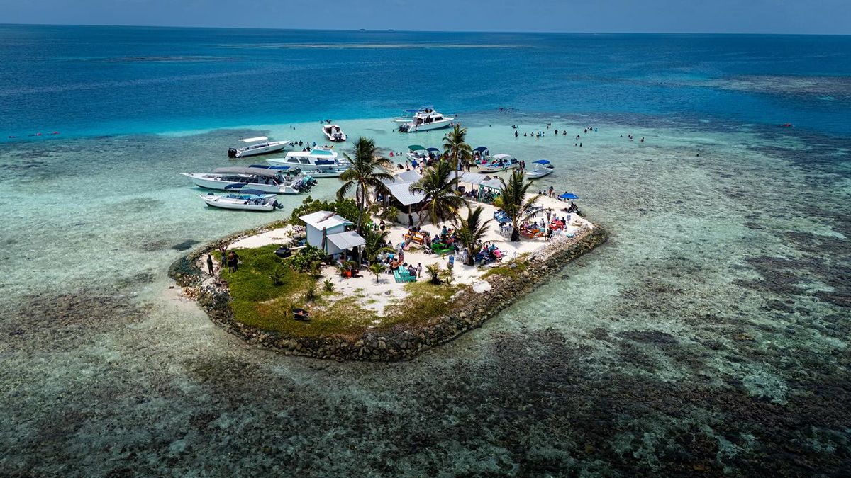 aerial of tiny island with many boats parked in front