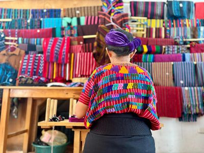 Alicia's mother giving a tour of her small textile shop lady in traditional clothes working textile