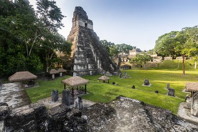 large mayan ruin surrounded by small thatched houses