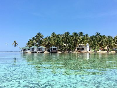 overwater bungalows on island with coconut trees