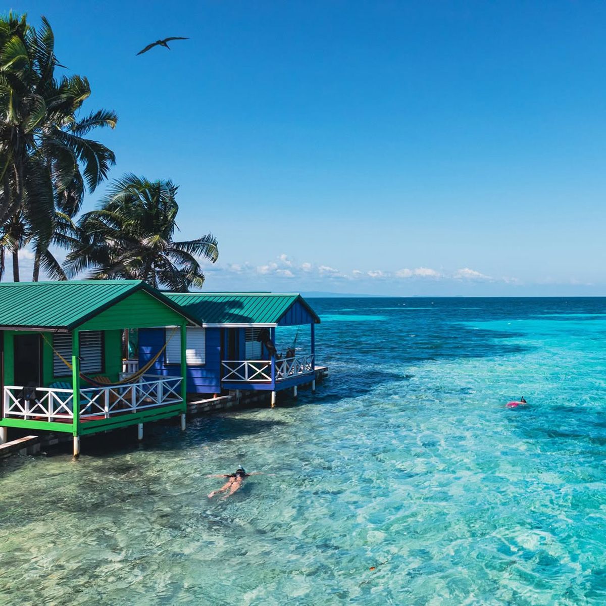 woman snorkeling in front of overwater bungalow