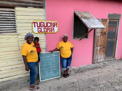 garifuna ladies and child in front of restaurant with chalkboard sign