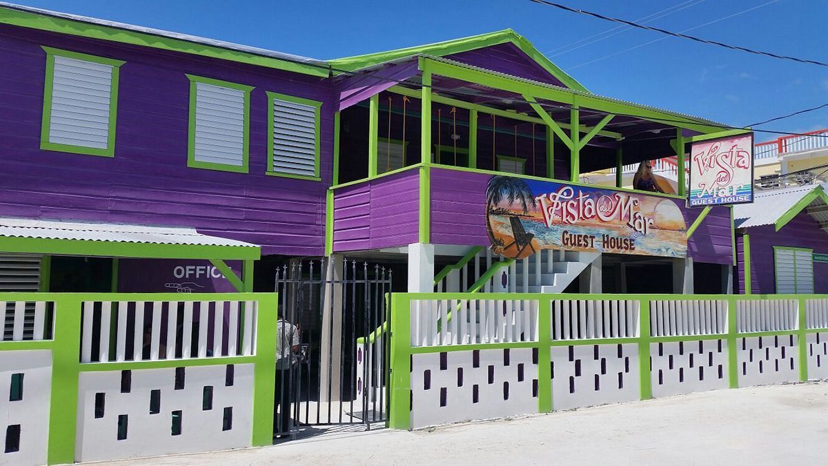 purple and green wooden house on sandy street